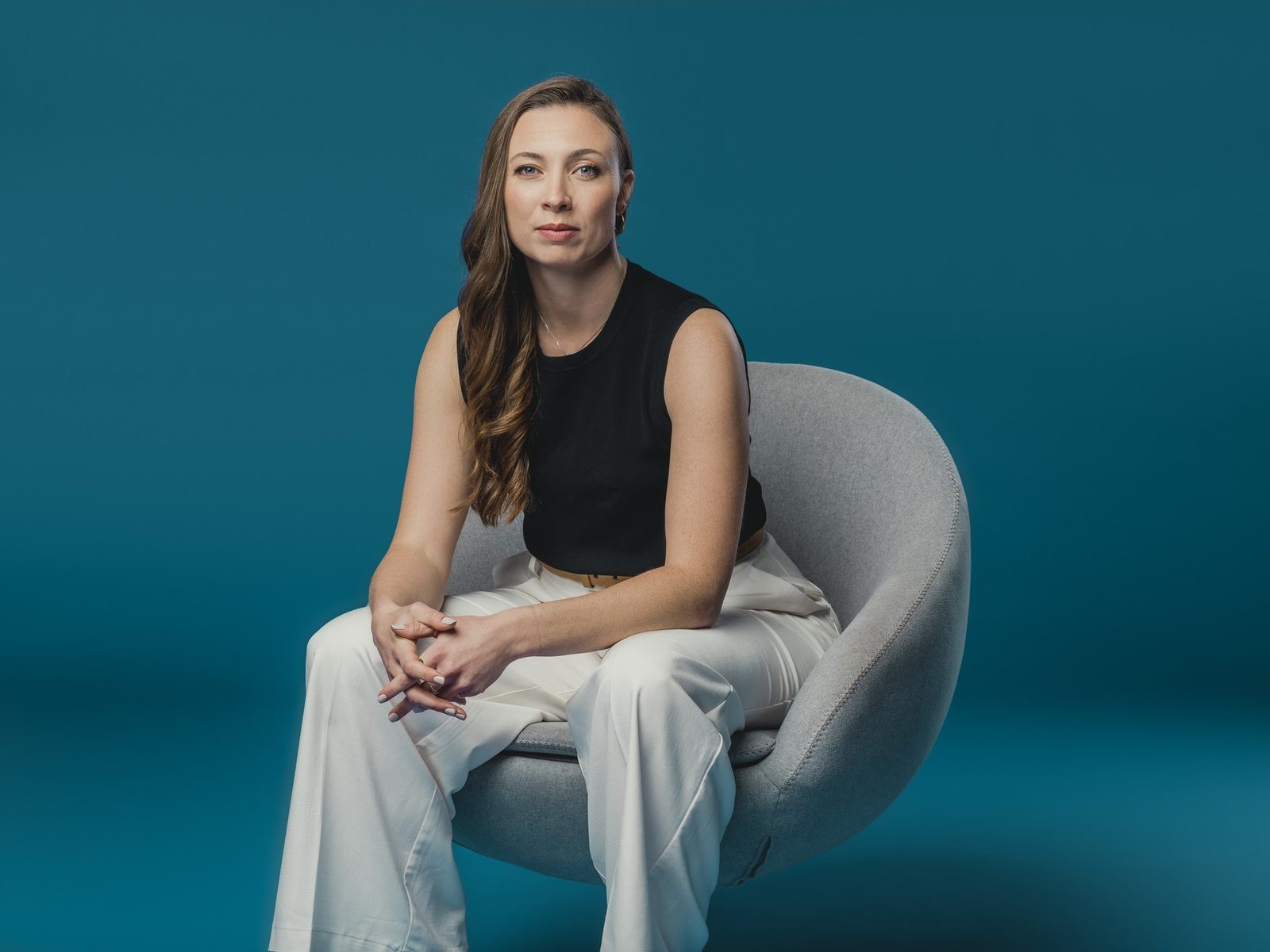 Dr. Jessica Metcalfe seated in a grey armchair against a teal backdrop